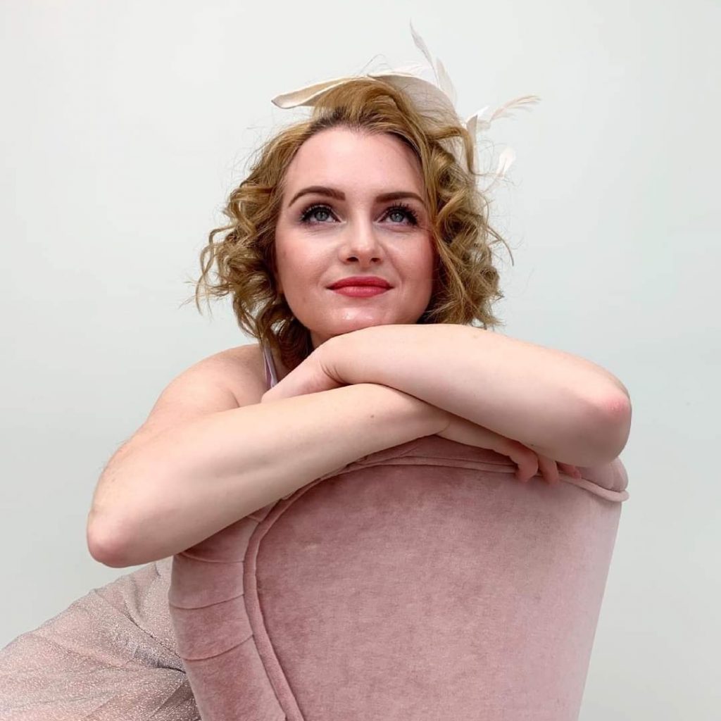 eine junge Frau in romantischen Style sitzt in rosanen Sessel